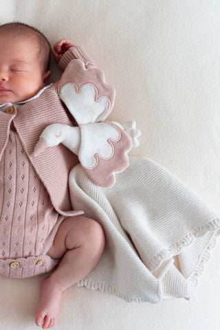 Sleeping baby with knitted stork comforter in pink and cream