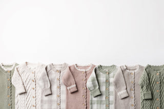Wooden rail with neutral knitted baby rompers on wooden hangers