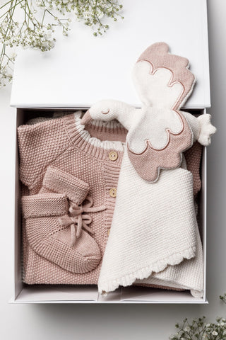 Sleeping newborn girl wearing knitted pink bow headband with knitted pink blanket