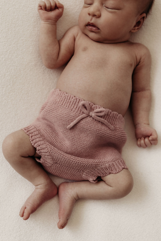 Baby asleep wearing pink knitted bloomers