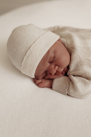 Baby asleep wearing knitted hat and romper