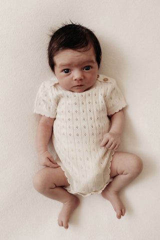 Baby in knitted beige bodysuit