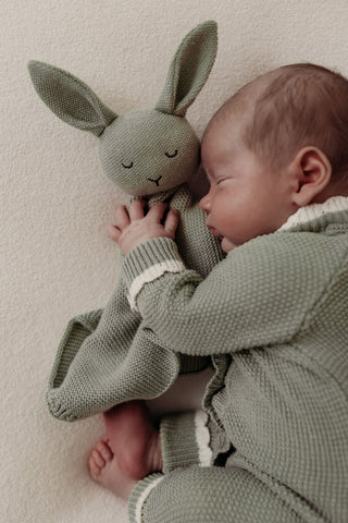 Sleeping baby cuddling sage green bunny comforter