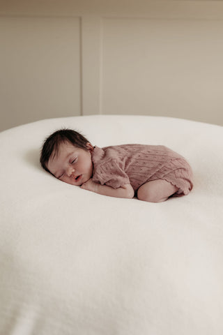 Sleeping newborn baby wearing pink knit bodysuit