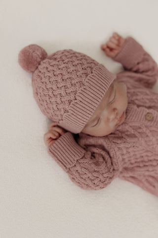 Baby wearing knitted pink hat and romper