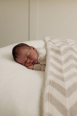 Sleeping baby with neutral chevron stripe knitted blanket