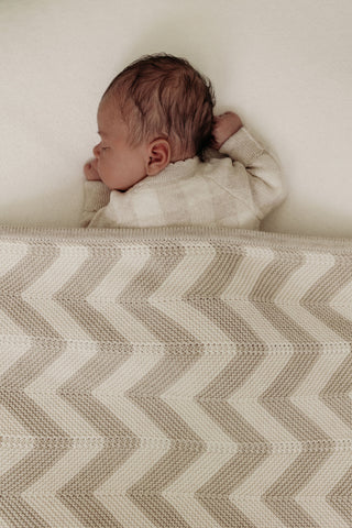 Sleeping baby with neutral chevron stripe knitted blanket