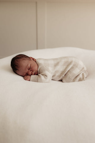 Sleeping baby wearing grey neutral check knitted romper