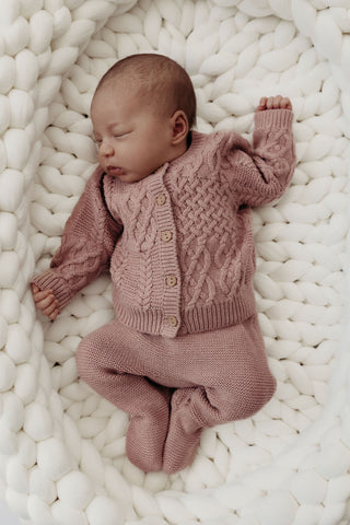 baby lying in knitted basket wearing knitted pink set
