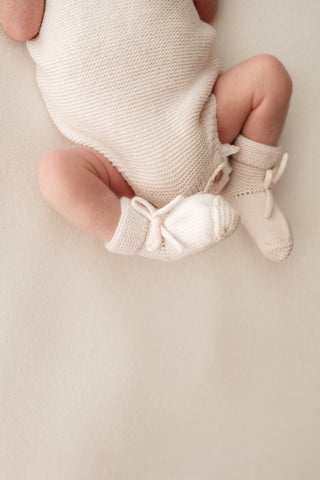 Baby feet wearing knitted cream bow booties