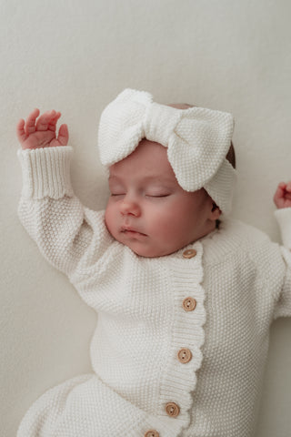 Baby wearing white bow headband and romper