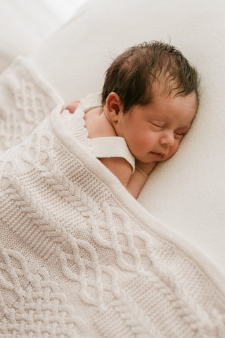 Sleeping baby under a cable knit blanket