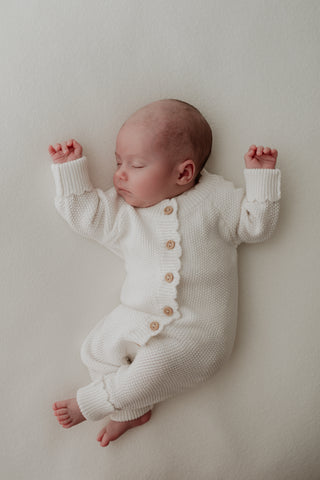 Baby sleeping wearing white button up knitted romper