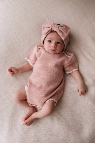 Baby wearing a knitted pink headband and bodysuit