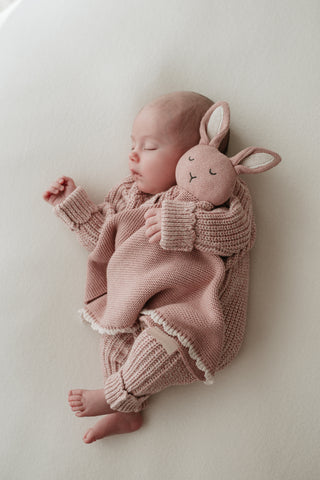 Sleeping baby cuddling a pink bunny comforter