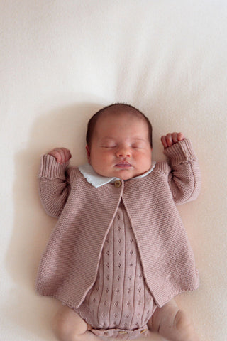 Sleeping newborn baby girl wearing pink knitted cardigan and bodysuit
