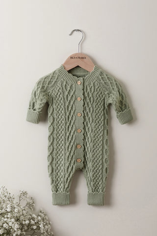 Sage cable knitted baby romper on a wooden Isla & Fraser hanger