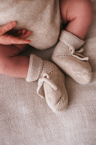 Knitted grey baby booties with a bow