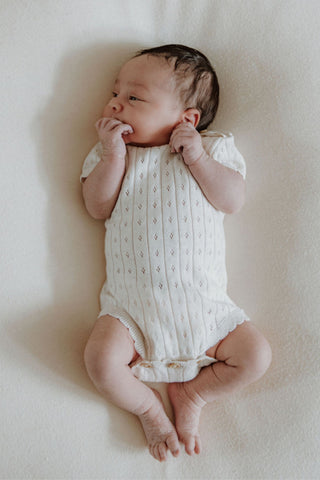 Newborn baby wearing knitted bodysuit