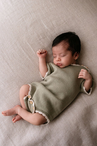 sleeping newborn wearing a sage green bodysuit
