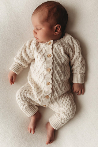 Sleeping newborn baby wearing knitted cable baby romper