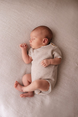 Baby wearing a neutral knitted romper