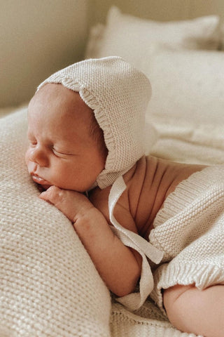 Sleeping baby with knitted bonnet and bloomers