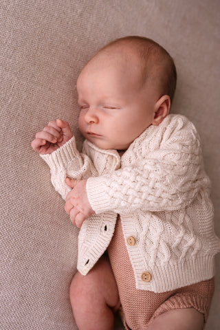 Sleeping baby wearing cable knit cardigan