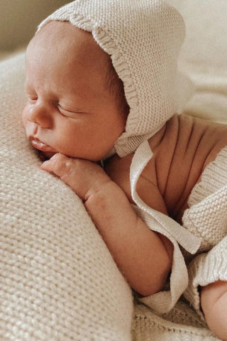 Sleeping baby wearing knitted bonnet