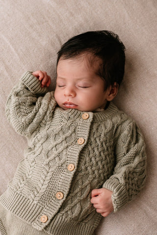 Newborn baby wearing sage green cable knit cardigan