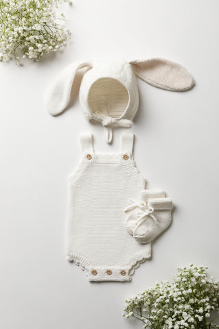 Gift Bundle containing a Milk White Bunny Ear Baby Bonnet, a Milk White Baby Romper and Milk White Baby Booties, on a white backdrop with gypsophilia in corners 
