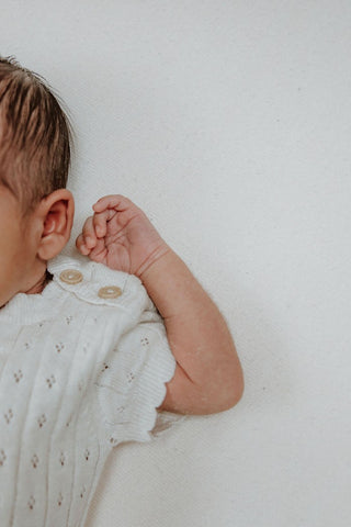 Knitted baby bodysuit shoulder button detail