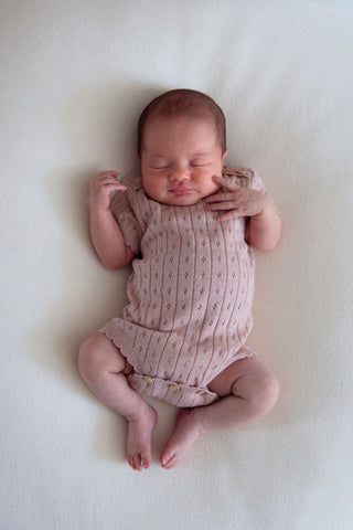 Newborn baby wearing pink knit bodysuit