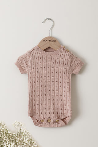 Pink Pointelle knit baby bodysuit on a wooden Isla & Fraser hanger