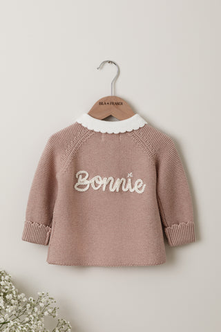 Knitted baby cardigan in pink with white collar and the name 'Bonnie' embroidered on the back
