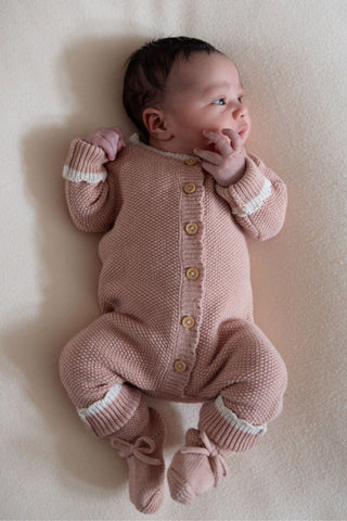 Baby in knitted pink romper and booties