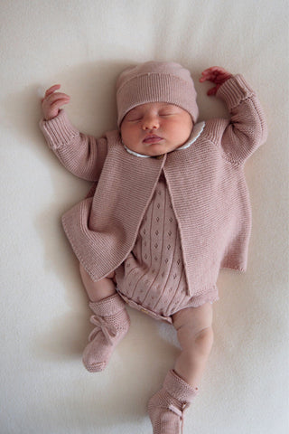 Sleeping baby in knitted pink outfit