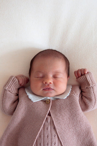 Sleeping newborn baby with pink cardigan with white collar