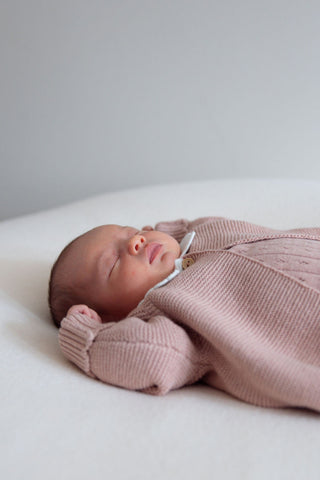 Sleeping baby girl wearing knitted pink outfit