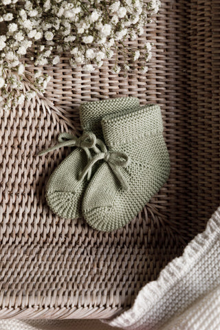 Sage Green Knitted Baby booties in basket with flowers