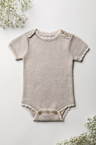 Neutral grey baby bodysuit with cream scalloped edges and button fastening on a white background