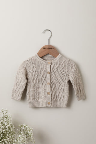 Neutral beige cable knit baby cardigan on an Isla & Fraser hanger 
