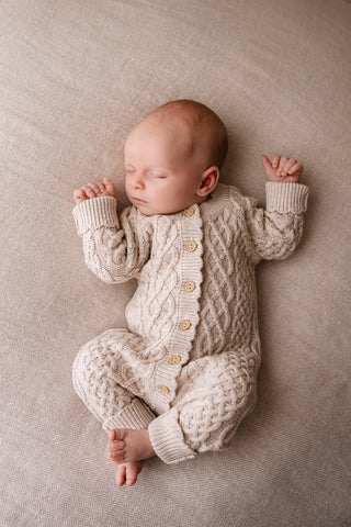 Sleeping baby wearing cable knitted romper